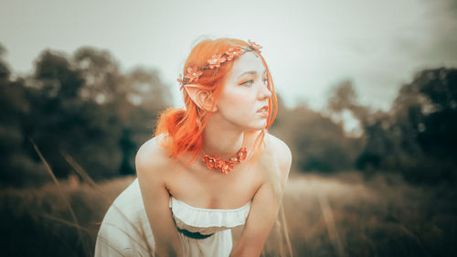 Portrait of young woman standing against trees