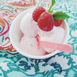 High angle view of ice cream with raspberries in bowl on table