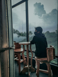 Man standing on table by window