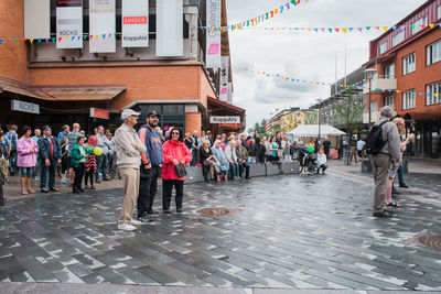 People in town square against sky in city