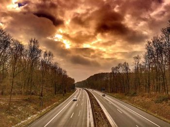 Country road against cloudy sky at sunset