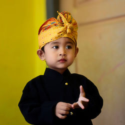 Portrait of young woman standing against yellow wall