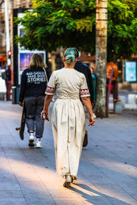 Rear view of people walking on footpath