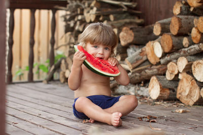Portrait of cute boy eating watermelon sitting outdoors