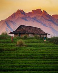 Built structure on field by mountains against sky