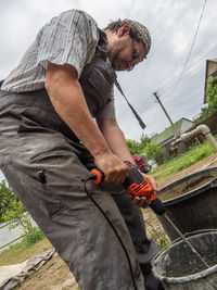 Caucasian man stirs tile glue with a manual electric drill in a bucket