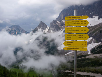 Information sign on snowcapped mountains against sky