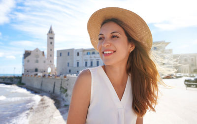 Holidays in italy. portrait of smiling relaxed woman on trani seafront, apulia, italy.