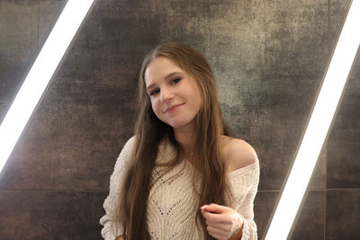 Portrait of smiling woman standing against wall