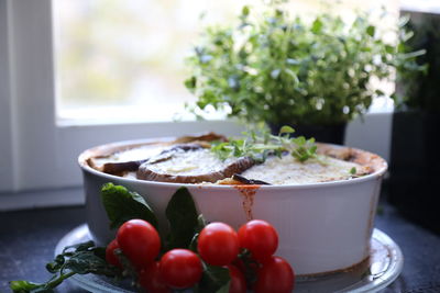 Close-up of food served in container with tomatoes on table