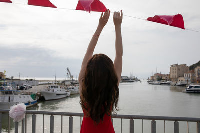 Rear view of woman holding bunting flag hanging at harbor