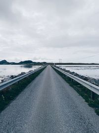 Empty road by bridge against sky