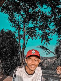 Portrait of smiling young man standing against trees