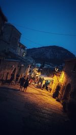 Street amidst buildings against sky at night