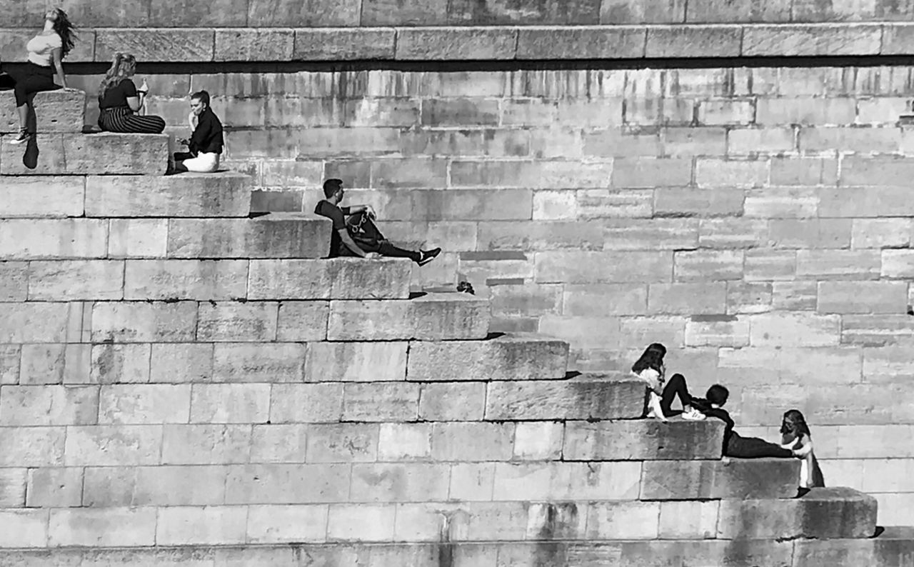 PEOPLE ON WALL BY STAIRCASE AGAINST BRICK WALLS