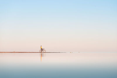 Cyclist on the shore of the calm sea. distant plan