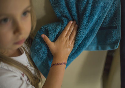 Close-up of girl drying hands by using towel at home