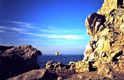 Rock formations by sea against blue sky