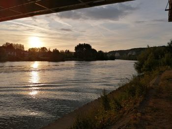 Scenic view of river against sky at sunset