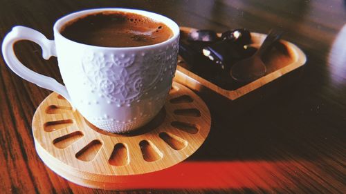 Close-up of coffee cup with dessert on table