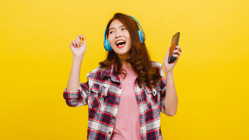 Full length of young woman standing against yellow background