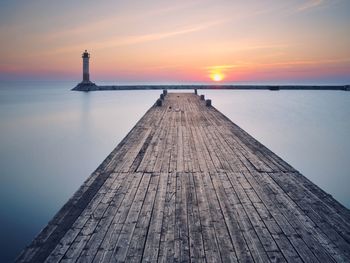 Pier over sea against sky during sunset