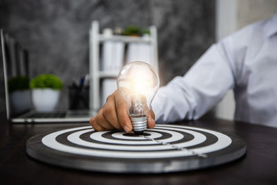 Close-up of man holding light bulb on table