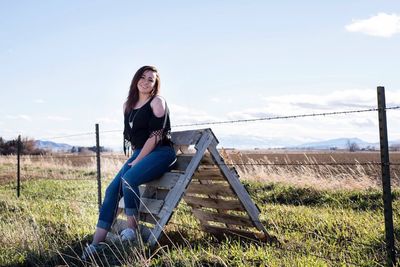 Woman sitting on swing against sky