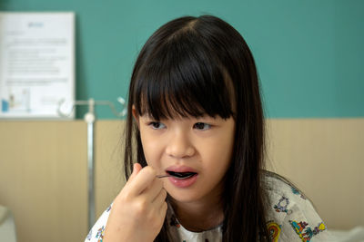 Close-up of girl eating food while sitting on bed in hospital