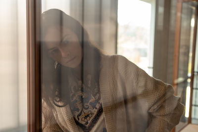 Portrait of young woman seen through glass