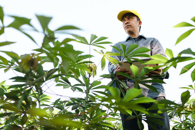 Low angle view of young man standing against plants