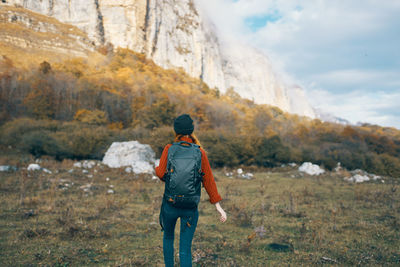 Rear view of man walking on rock against sky