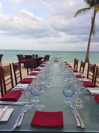 Chairs and tables at restaurant by sea against sky