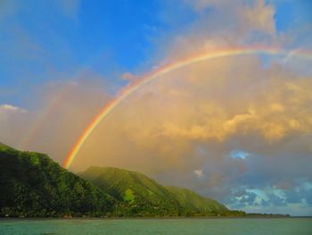 Scenic view of rainbow over sea against sky