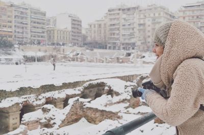 Woman leaning on railing by city