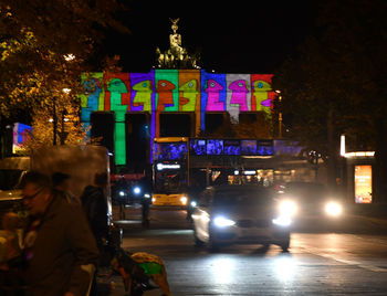 Cars on illuminated city street at night