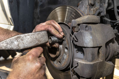 Unscrewing the old brake disc from the car with a bit wrench, hammer tapping on the bolt.