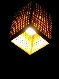 Low angle view of illuminated electric lamp against black background