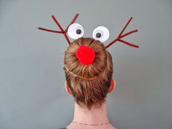 Rear view of woman wearing decoration on hair bun against wall