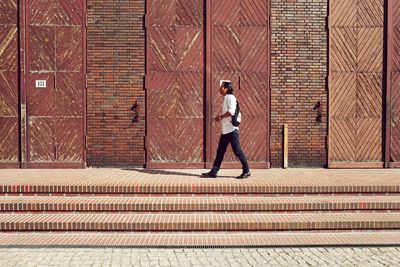 Full length of man standing against brick wall in city