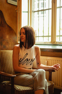 Young woman sitting on chair by window