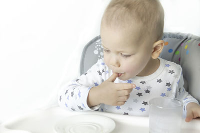 A little boy in a sweater with stars licks his fingers after a delicious meal.