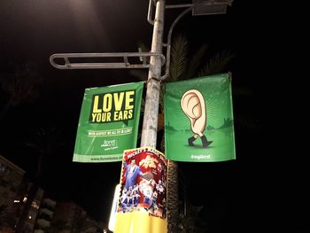 Low angle view of illuminated sign hanging at night