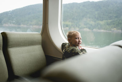 Portrait of boy sitting by window while travelling in train