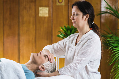 Smiling woman giving massage to client at spa
