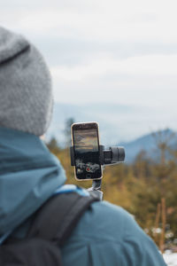 Rear view of man photographing on mobile phone