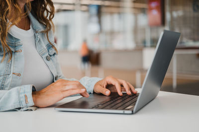 Midsection of woman using laptop on table