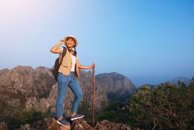 Woman standing on rock against sky