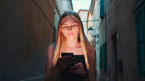 Young woman using mobile phone while standing on building