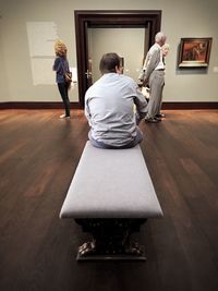 Rear view of man sitting on tiled floor